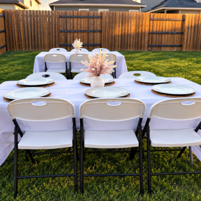 White six-foot event table with chairs and linens at an outdoor setup